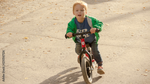 Happy little boy looks ahead and runs on a runbike photo