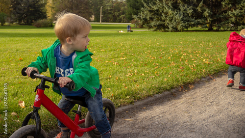 A 5-year-old boy sits on a bicycle and looks back at the departing girl.