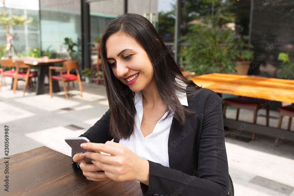 Portrait of happy young woman reading or texting message. Caucasian businesswoman or student networking on smartphone in cafe. Mobile communication concept