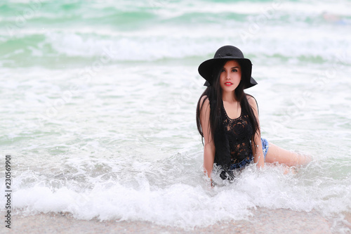 portrait of fashion and beautiful girl with black hat on the beach © feeling lucky