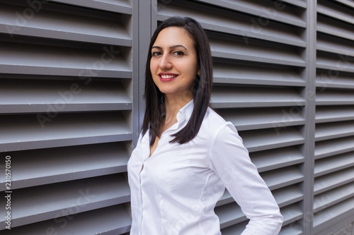 Portrait of smiling confident young Caucasian businesswoman wearing white shirt. Happy female student posing outdoors. Businesswoman concept