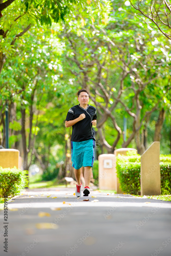 Obraz premium Young man in sports clothing jogging in park with headphone
