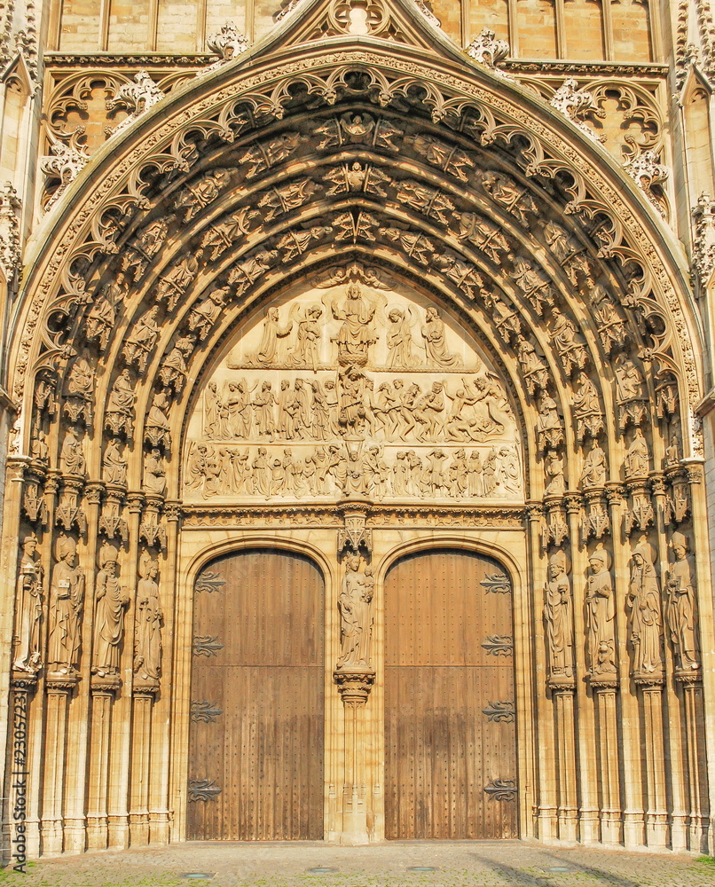 The gates of the ancient Catholic Gothic temple are decorated with sculptures and bas-reliefs.