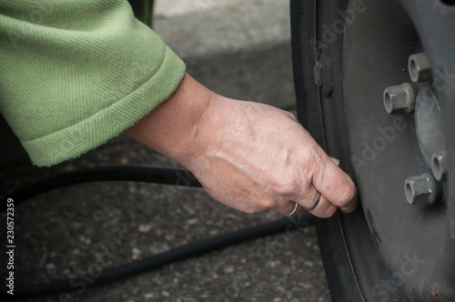 closeup of woman hand putting air into the tire from tire valve stem © pixarno