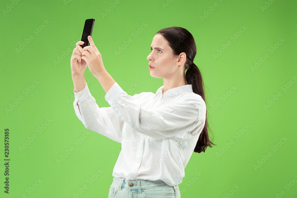 Portrait of a confident happy smiling casual girl making selfie photo by mobile phone isolated over green background. Portrait of a confident happy smiling casual girl making selfie photo by mobile phone isolated over green background.