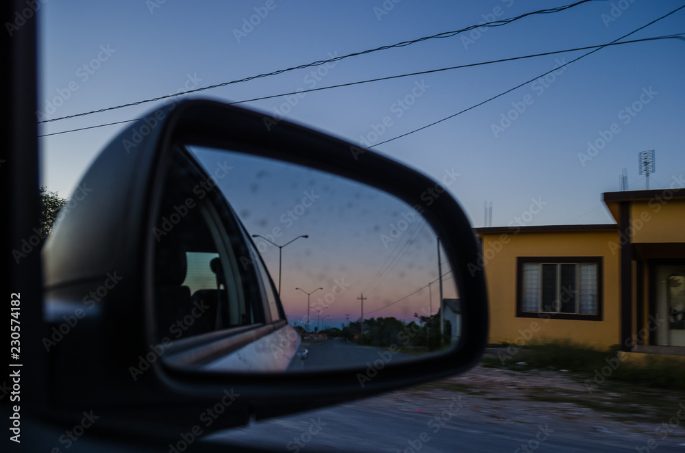Road from the inside of a car and the reflection of the rear-view mirror of the car. road trip at sunset