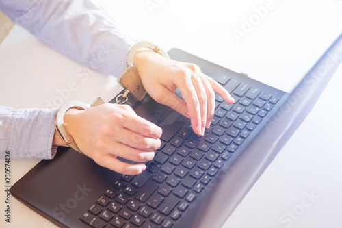 Woman hands locked to laptop by chain on keyboard of notebook photo