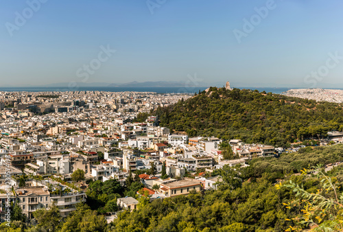 Athens city panorama with a green hill and aegean see on horizon. © juhrozian