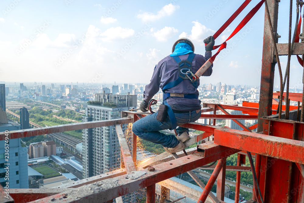Construction worker wear standard personal protective equipment dismantle steel structure at height rise building project Construction worker wear standard personal protective equipment dismantle steel structure at height rise building project