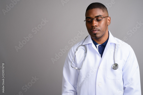 Young handsome African man doctor against gray background © Ranta Images