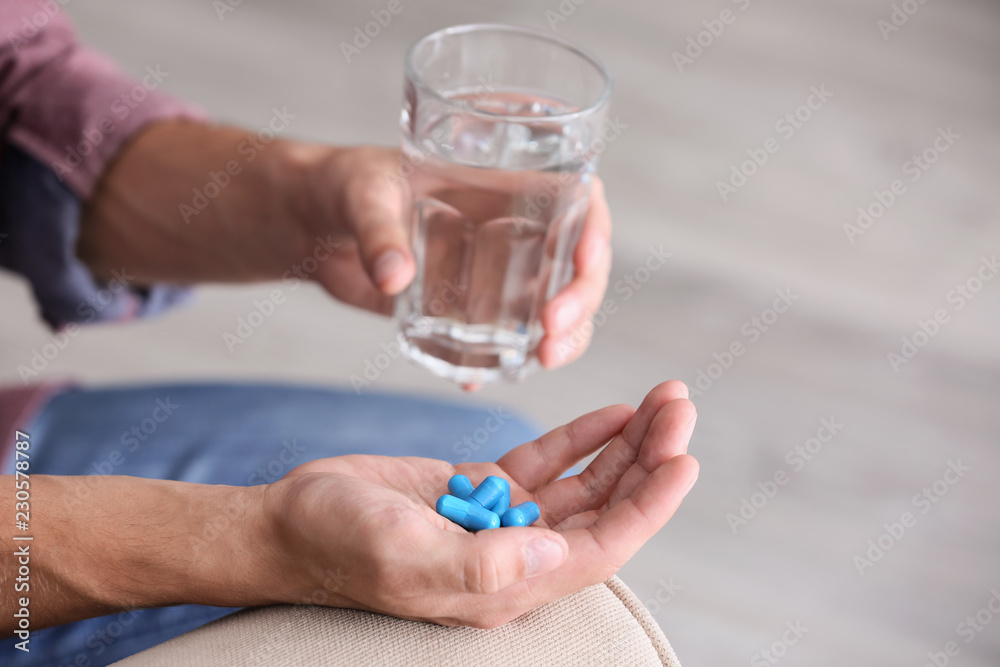 Man holding pills and glass of water, closeup Man holding pills and glass of water, closeup