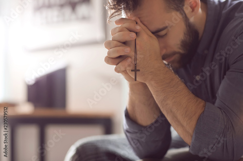 Religious young man praying to God at home