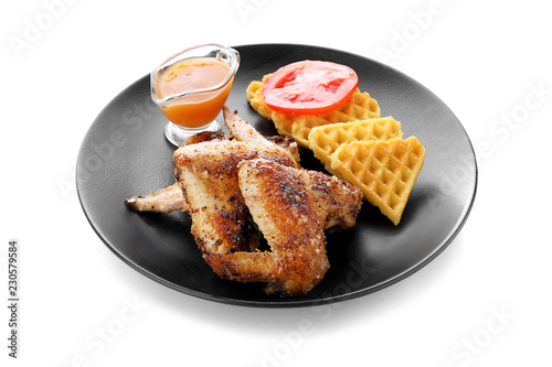 Delicious waffles with chicken wings and sauce on plate, isolated on white