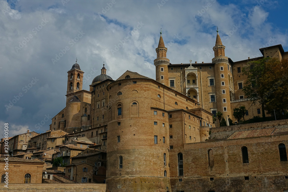 Beautiful historic town of Urbino and stone buildings under the cloudy blue sky.