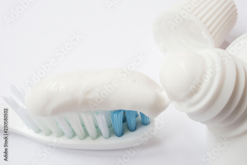 Squeezing toothpaste onto toothbrush on white background