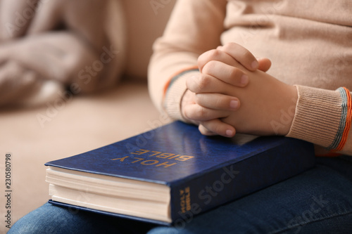 Little boy with Bible praying at home, closeup
