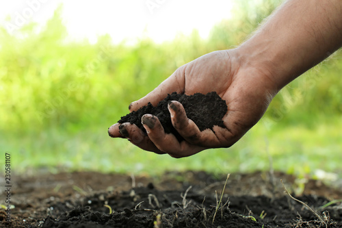 Man holding black soil outd...