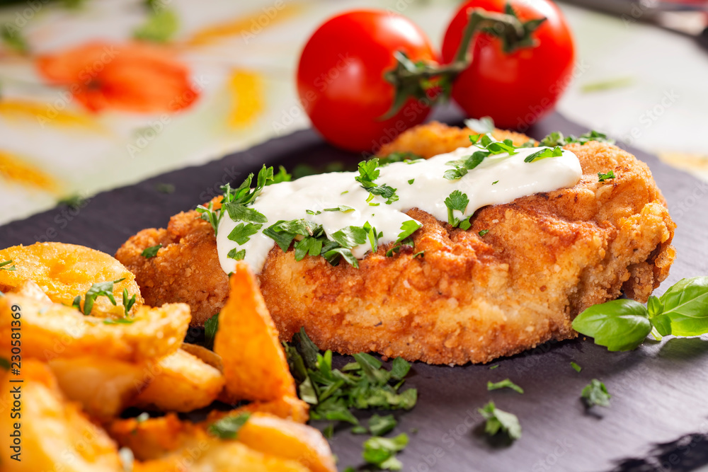 Pork schintzel with a white sauce, fries and herbs