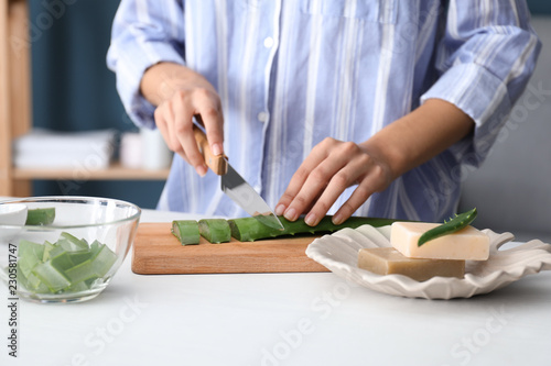 Female hands cutting aloe leaf at table