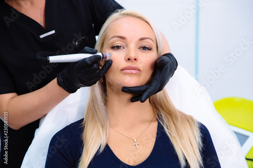 A cosmetologist carries out procedures on the patient's face with a hydro-peeling apparatus. Cleansing and rejuvenation of the skin of women with new technologies. Cosmetology concept in clinic. photo