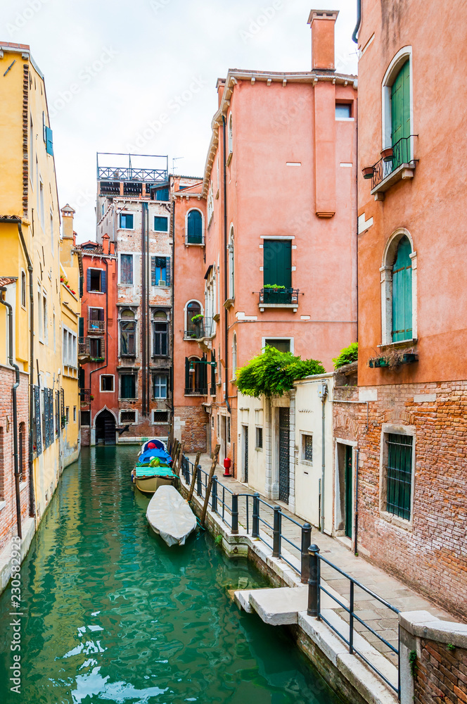 Colorful water canal street with parked boats in Venice Italy