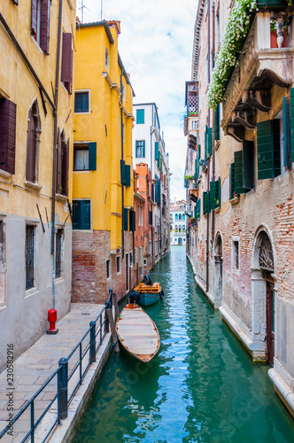 Colorful water canal street with parked boats in Venice Italy