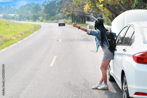 Young asian traveler with backpack and map hitchhiking on the road while traveling during holiday vacation © feeling lucky
