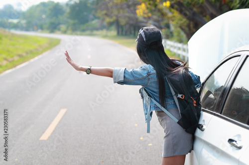 Young asian traveler with backpack and map hitchhiking on the road while traveling during holiday vacation