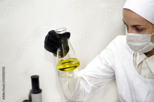  laboratory worker in a white coat working with chemicals under a microscope