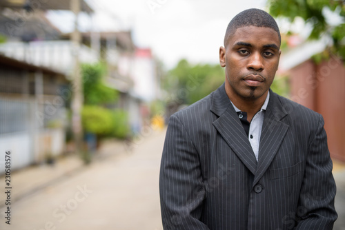 Young handsome African businessman wearing suit in the streets o