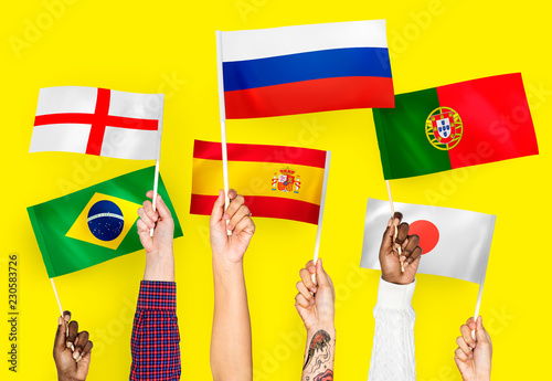 Hands raising national flags of England, Spain, Japan, Portugal, Russia, and Brazil photo