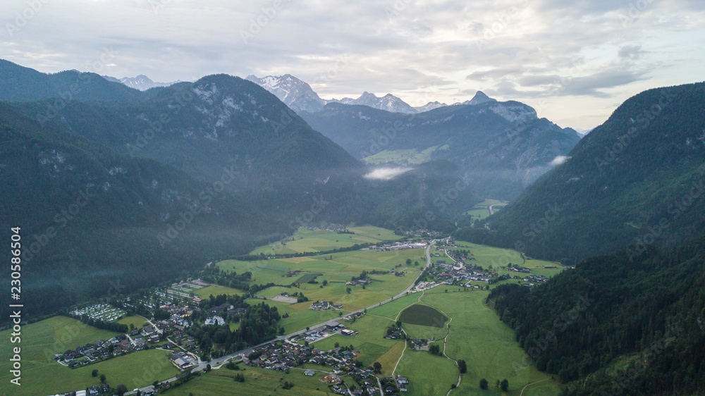 Fototapeta premium Aerial view of the morning foggy landscape in the alpine mountains