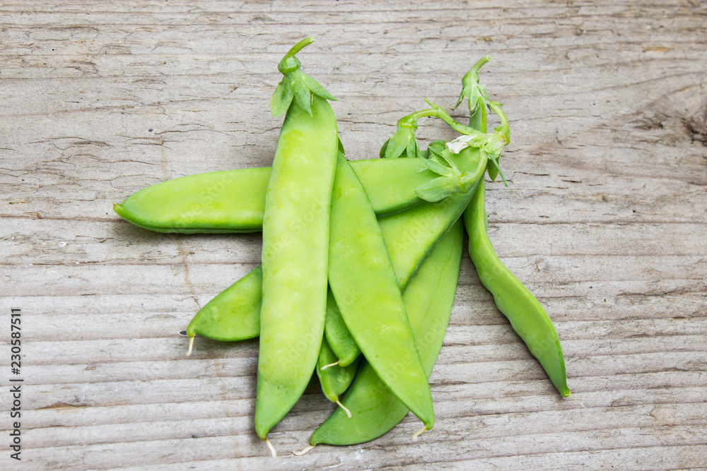 Pods of green peas on the background of old wood. The concept of vegetarianism and healthy eating. Copy space.