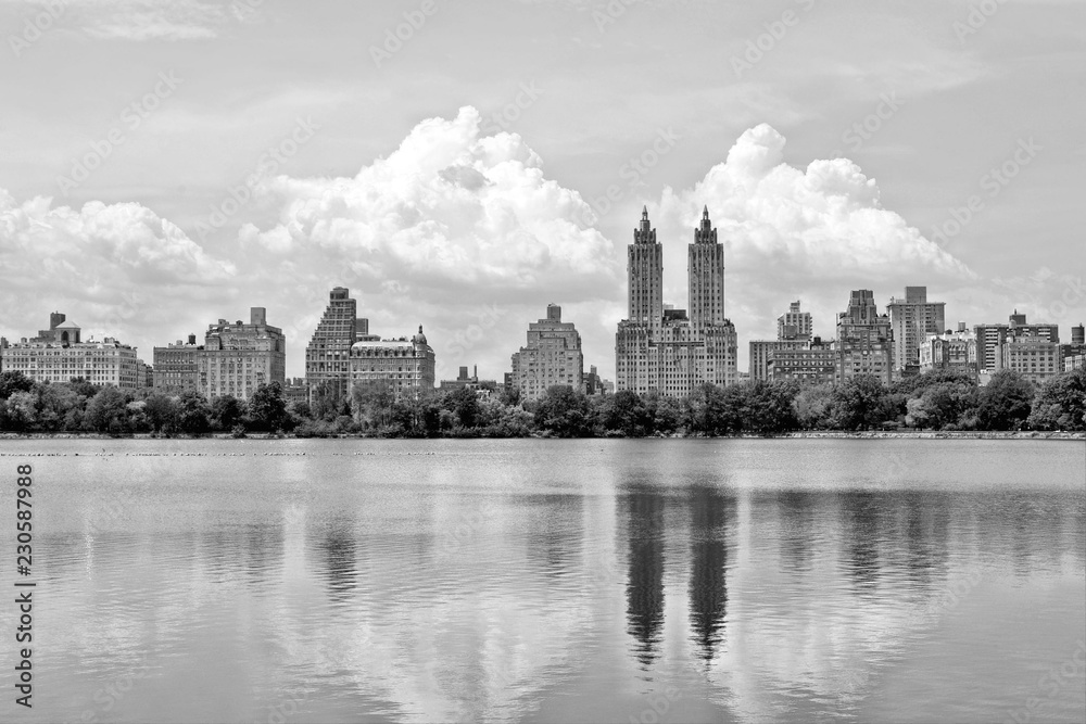 black and white cityscape with skyline of skyscrapers and water reflections on big lake in central park, manhattan new york, usa