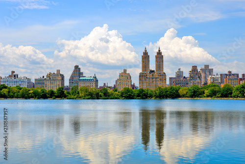 cityscape with skyline of skyscrapers and water reflections on big lake in central park, manhattan new york, usa