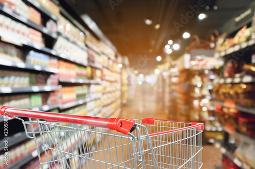 Foto supermarket aisle blurred background with empty red shopping cart