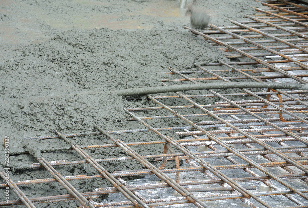 The wet concrete is poured on a steel reinforcement bar to form strong