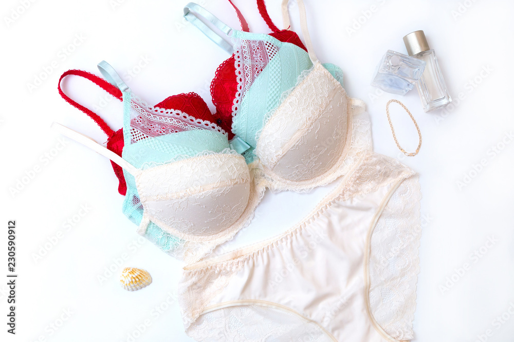 Set of colourful push up bras and panties, two bottles of perfume, gold bracelet and a shell on white background Set of colourful push up bras and panties, two bottles of perfume, gold bracelet and a shell on white background