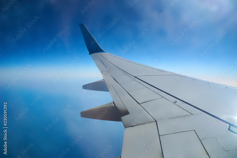 View from a landing airplane out the window travel. Wing of an airplane flying above the clouds over tropical island Turkey. Wing of airplane flying above the clouds in the sky