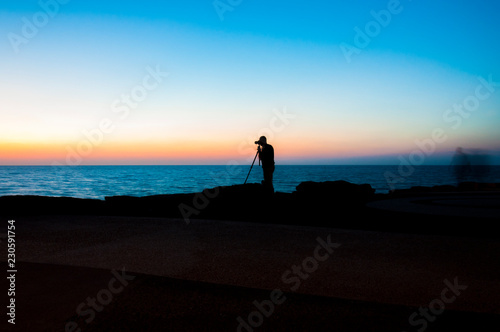 Photographer with tripod shooting sea sunset in Tel Aviv Israel
