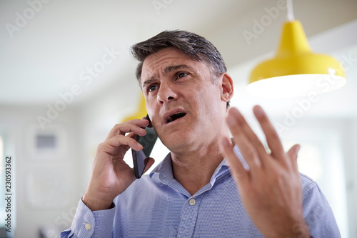Frustrated Mature Man Receiving Sales Call At Home photo