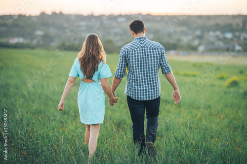 Young couple walking on the green grass in the field photo