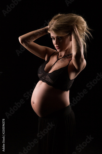 portrait of a pregnant woman in a dark background © Volodymyr Shcerbak