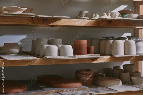 ceramic bowls and dishes on wooden shelves at pottery studio photo