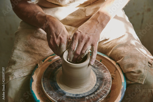 close up view of male potter hands working on pottery wheel at workshop
