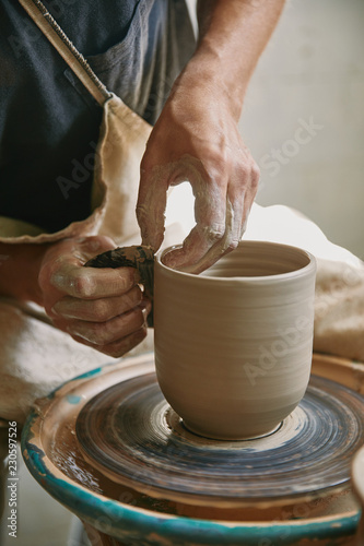 Fotografía partial view of male craftsman working on potters wheel at pottery studio