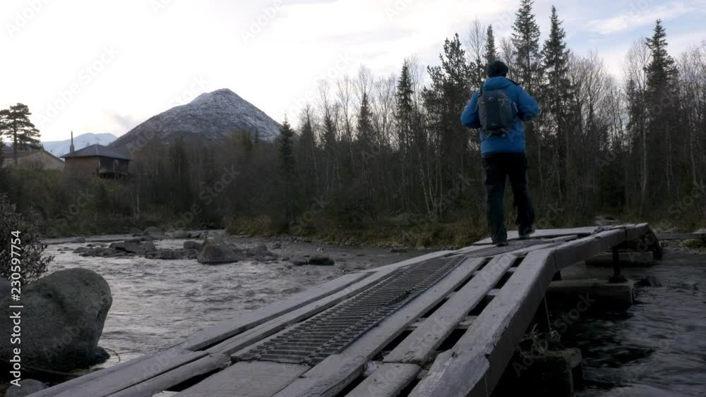 A man travels through a beautiful park. He crosses the mountain river on the bridge. Beautiful view of the mountains. A man travels through a beautiful park. He crosses the mountain river on the bridge. Beautiful view of the mountains.