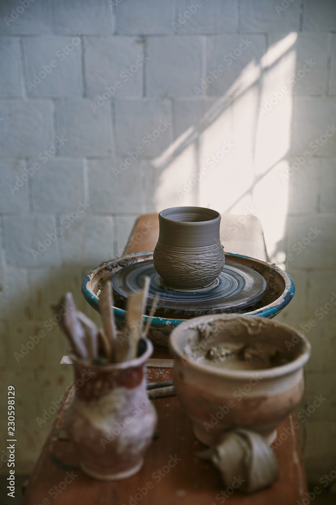 selective focus of clay pot on pottery wheel at workshop
