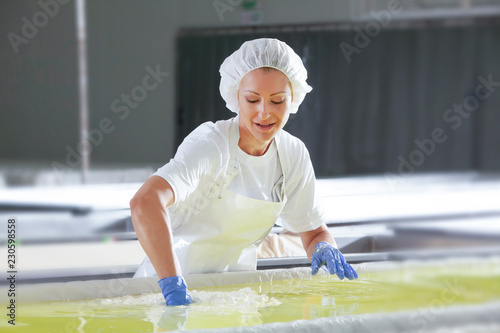 Female worker on white feta cheese production line in an industrial factory photo