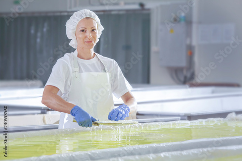 Female worker on white feta cheese production line in an industrial factory